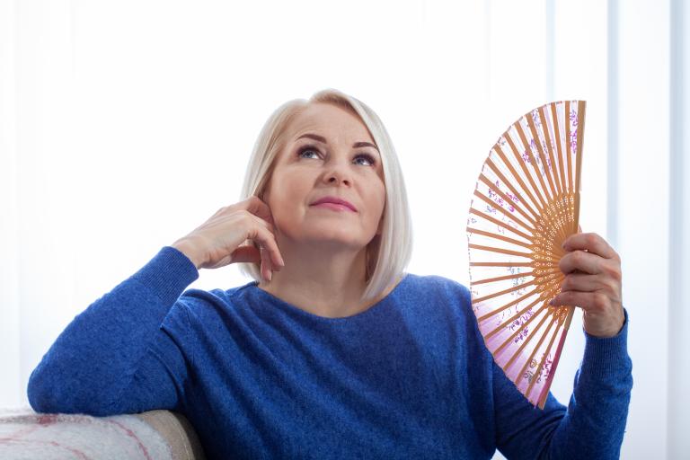 Woman fanning her face with a delicate fan.